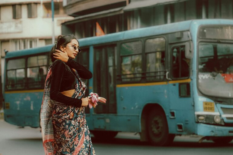 Elegant Indian woman posing in traditional saree by a blue city bus in Pune, India.