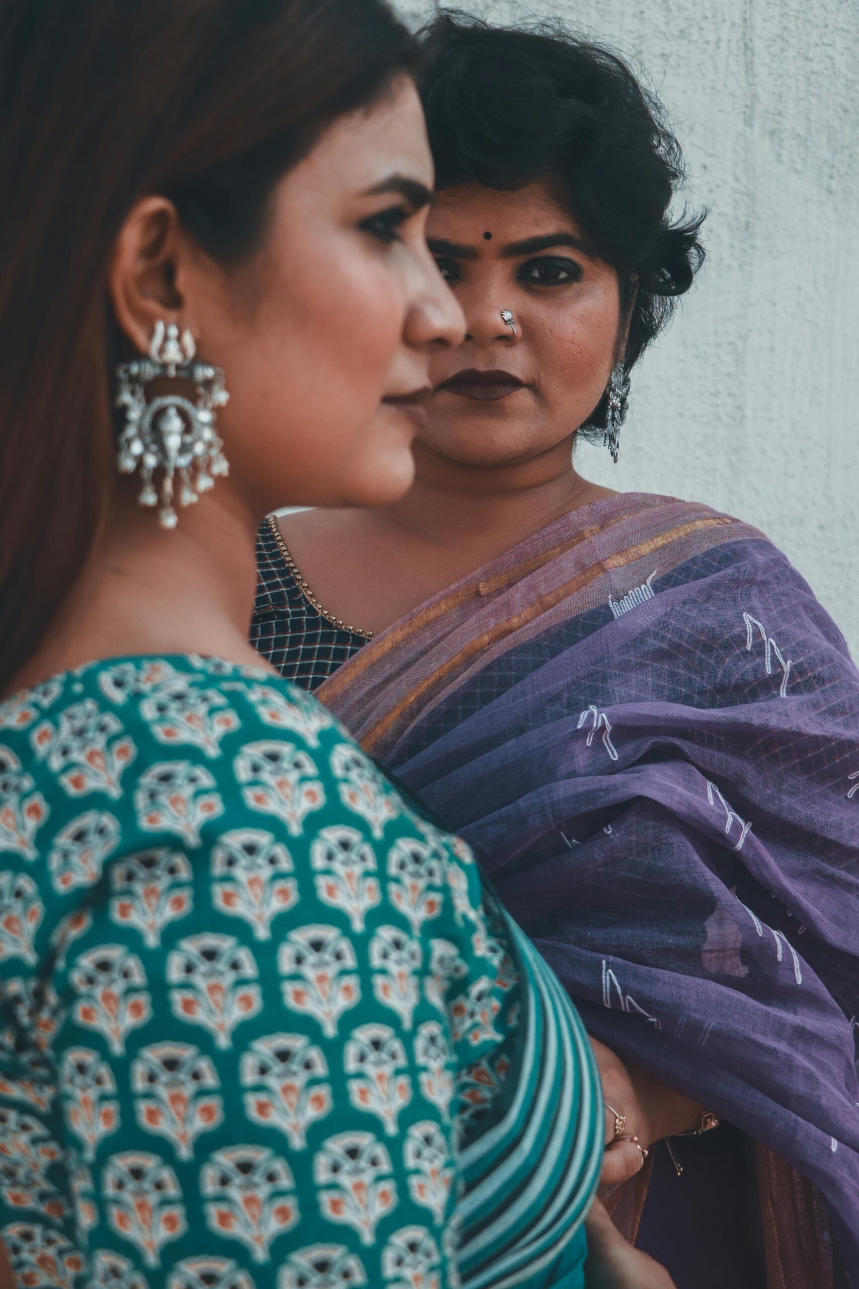 Portrait of two Indian women posing in traditional sarees, showcasing cultural elegance.